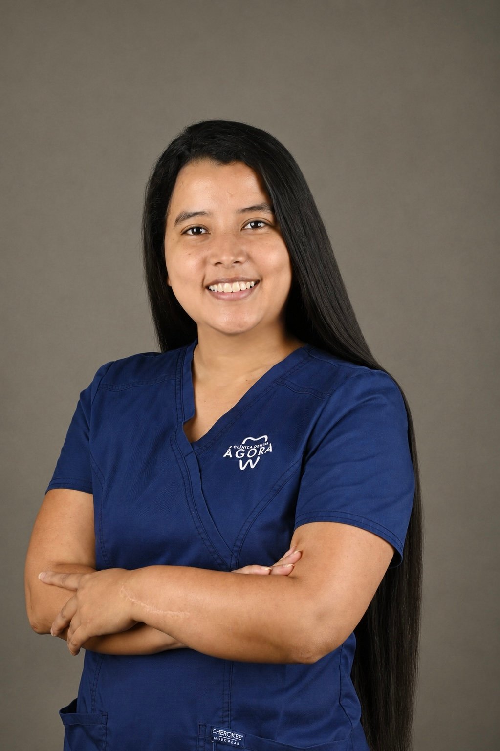 Retrato profesional de Paula Santana Domínguez, responsable de Atención y Acompañamiento de Pacientes en Clínica Dental Ágora, sonriendo con los brazos cruzados frente a un fondo gris